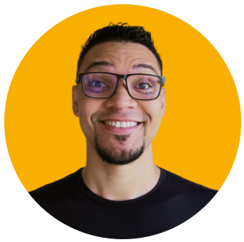 foto de perfil de mayk brito sorrindo,usando oculos e camisa preta e fundo amarelo.